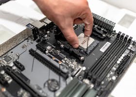 Person's hand installing a CPU on a motherboard, showcasing PC maintenance and repair.